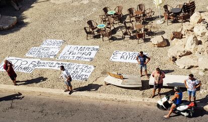 Residentes de Lampedusa ponen pancartas en señal de protesta contra el Gobierno central ante la falta de gestión de la inmigración en la isla, este lunes.