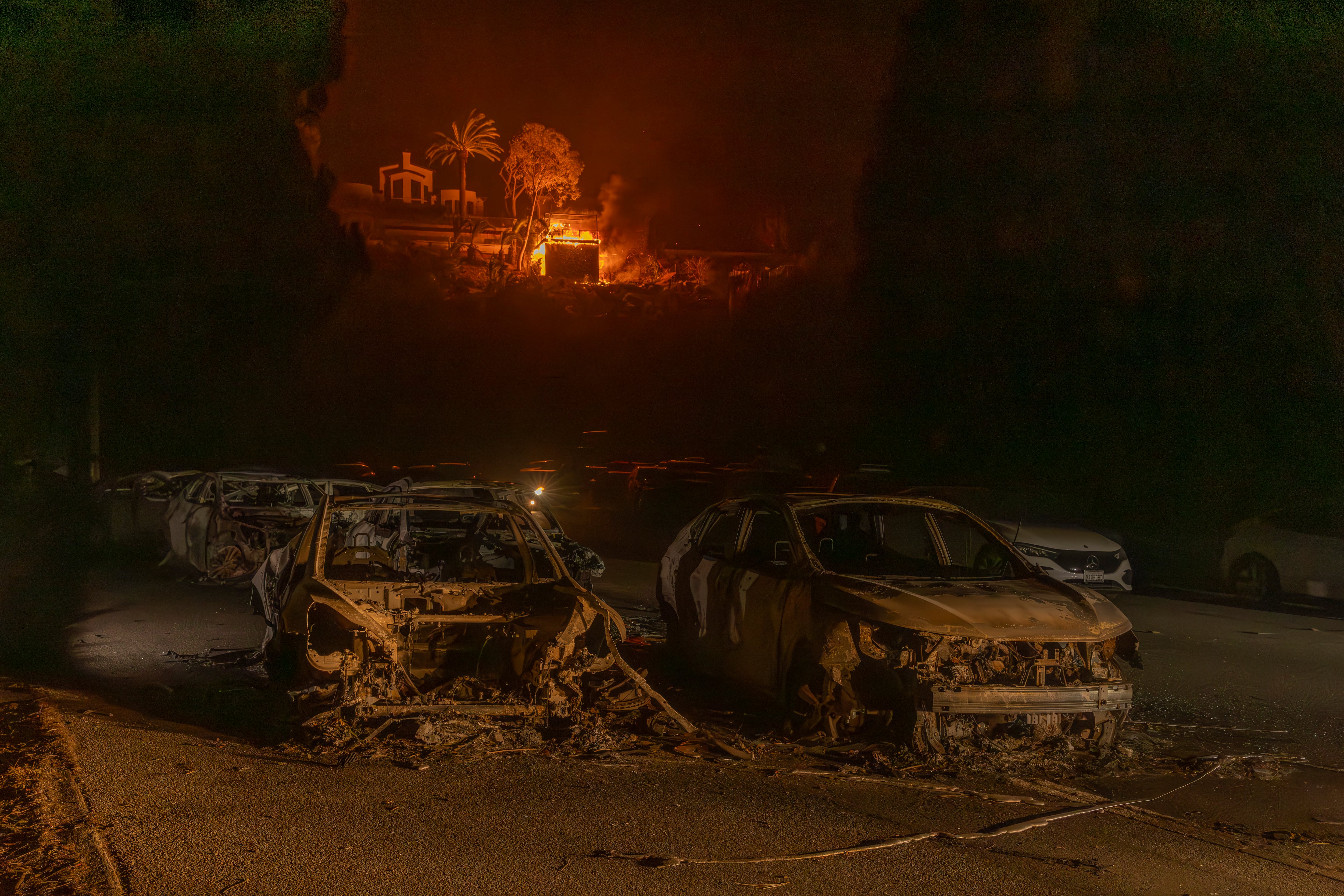 Varios coches calcinados ante un edificio en llamas, en el incendio de Pacific Palisades, Los Ángeles, California, el 8 de enero de 2025.