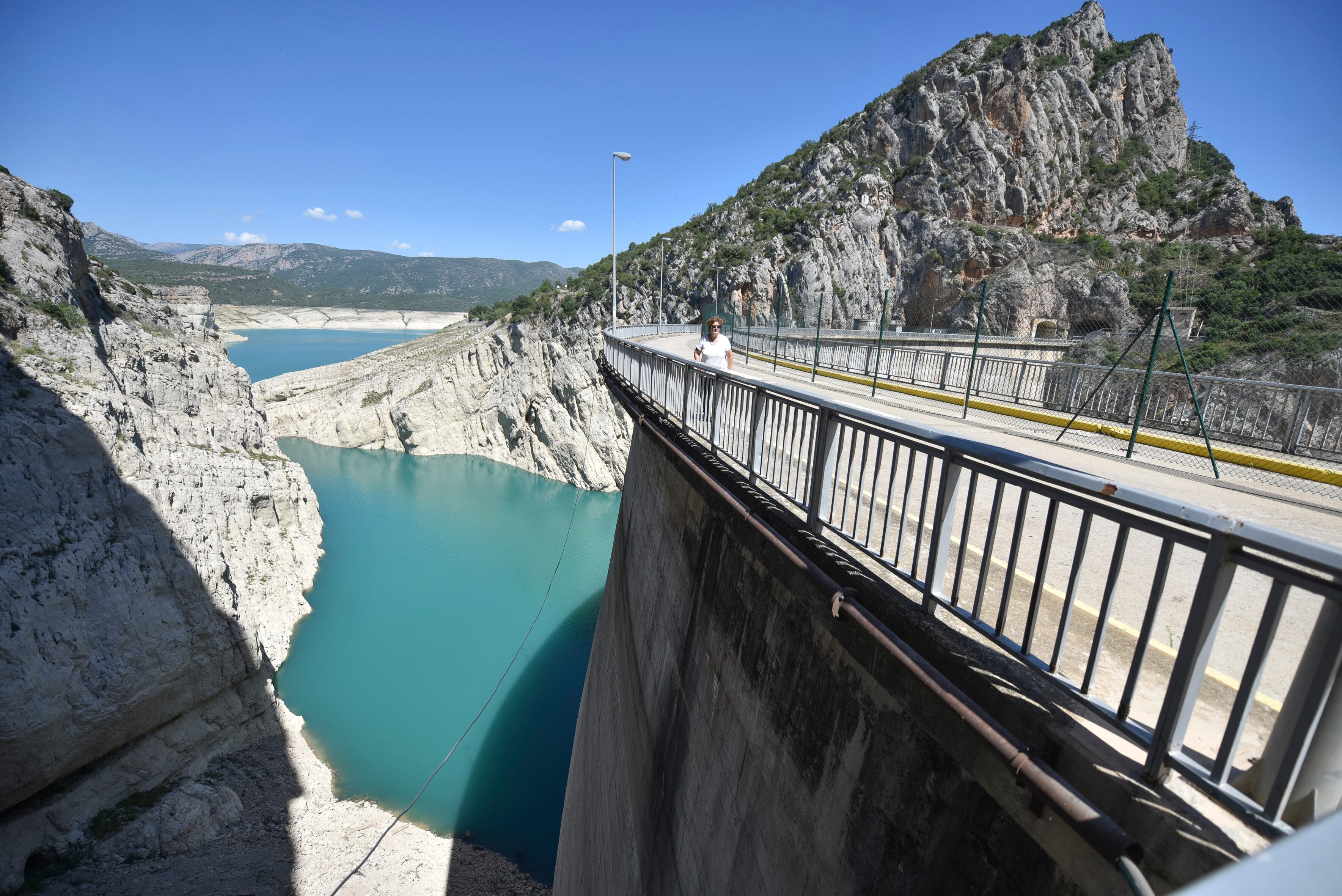 Una mujer pasa por la carretera que atraviesa el embalse de Canelles.