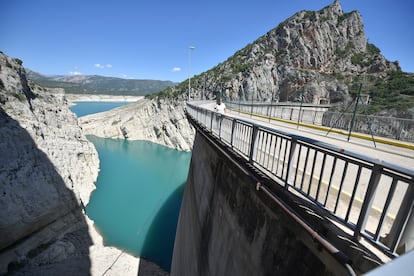 Una mujer pasa por la carretera que atraviesa el embalse de Canelles.