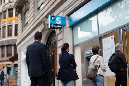 Colas en el exterior de una oficina del banco Sabadell en Barcelona.