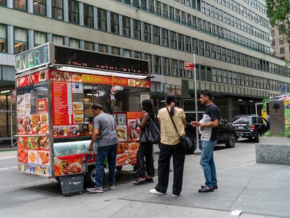 Varias personas esperan para comprar perritos calientes en un puesto de Manhattan (Nueva York).