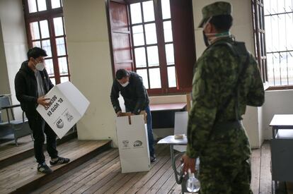 Trabajadores electorales montan una urna antes de abrir una mesa de votación durante la segunda vuelta de las elecciones presidenciales, en Quito, Ecuador. 