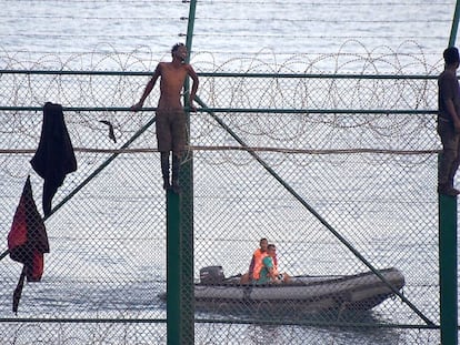 Migrants jump the border fence into Ceuta.