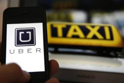 Logo de Uber en un móvil junto a un taxi.