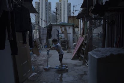 Un niño de cinco años juega fuera de su pequeña casa, hecha de hormigón y metal corrugado, en la terraza de un bloque de apartamentos. Vive en una choza ilegal en la azotea, al lado de una urbanización pública, que se ve al fondo.