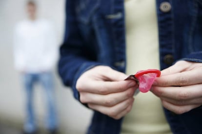 Un joven sujeta un preservativo.