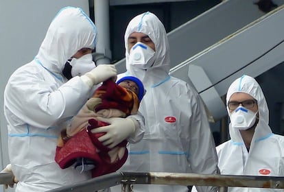 Personal de rescate sostiene a un bebé a su llegada al puerto de Taranto (Italia), tras ser rescatado junto a otros 200 inmigrantes de las aguas del Mediterráneo.