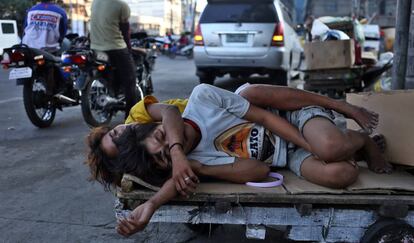 Dos personas duermen en la calle, sobre una carretilla en el mercado callejero de Divisioria, en el distrito de Tondo, en Manila.