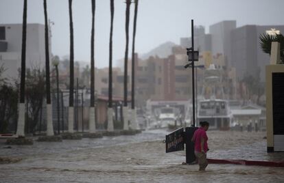 Mujer intenta caminar en una calle inundada por las lluvias torrenciales causadas por el huracán Newton en Cabo San Lucas (México). 