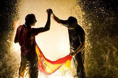 Dos aficionados se bañan en una fuente de la Plaza de España para celebrar la victoria de España.