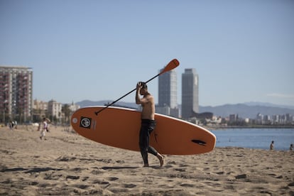 Un hombre con un paddle surf este martes en la playa de la Barceloneta.