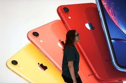 An Apple Store employee walks past an illustration of iPhones at the new Apple Carnegie Library during the grand opening and media preview in Washington