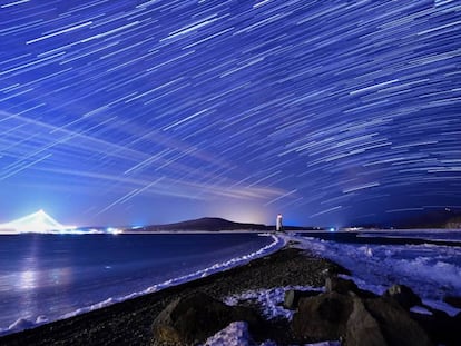 Lluvia de estrellas de las Gemínidas durante su pico, en el cielo nocturno sobre el faro de Tokarevsky en el cabo de Egersheld en la isla de Russky en el mar de Japón.