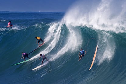 Varios surfistas cogen una ola en una playa de al norte de Oahu, en Hawái.