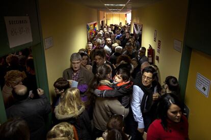 Los electores hacen cola para votar mientras se cruzan con los que salen después de ejercer su voto en un colegio electoral de Madrid.