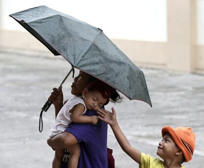 Un hombre lleva a sus dos hijos a la escuela del distrito de Baseco, en Manila, reconvertida en centro de evacuación. En la ciudad continúan las evacuaciones de las personas que viven cerca del mar