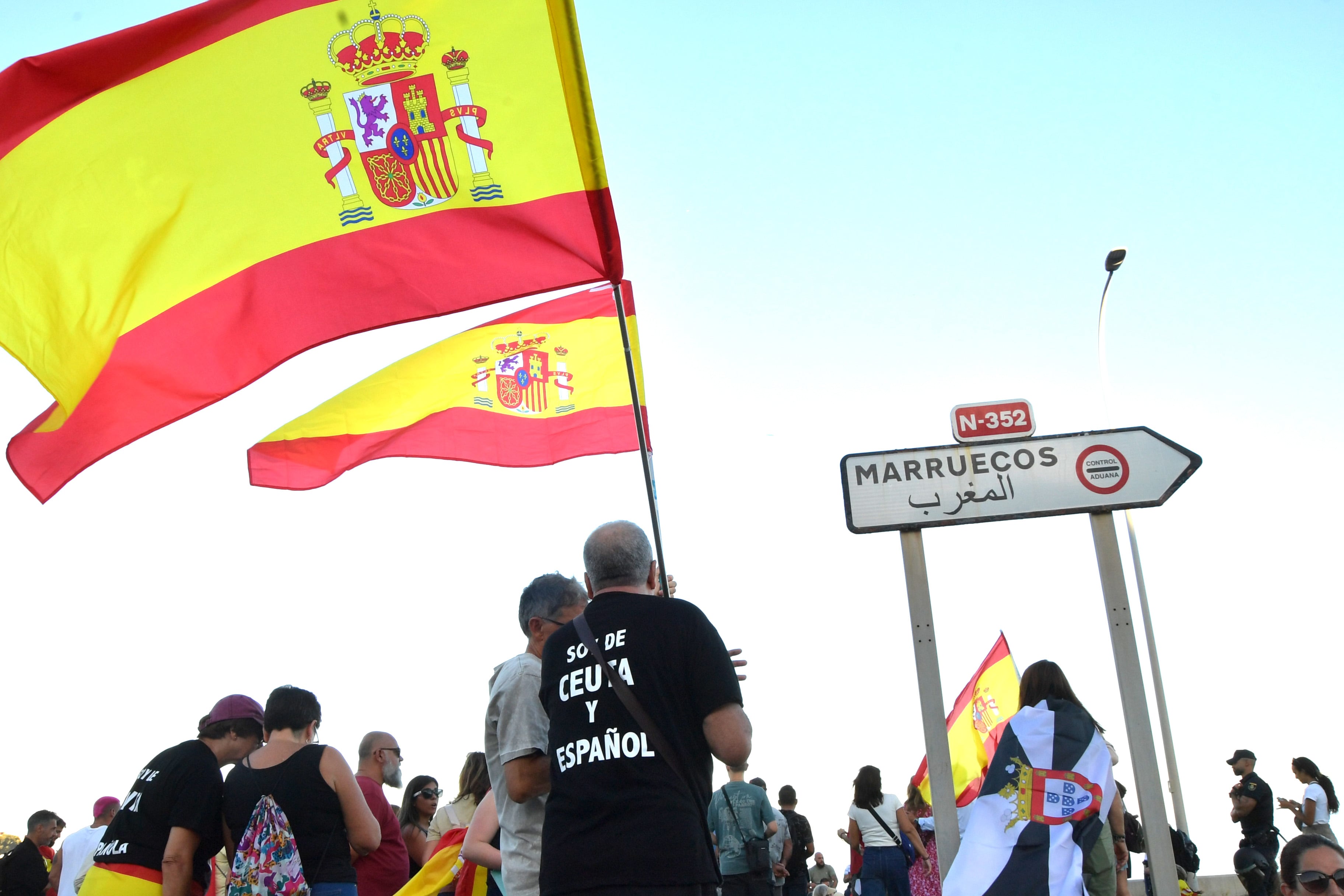 Dos hombres sujetan dos banderas de España durante la manifestación de este sábado en Ceuta.