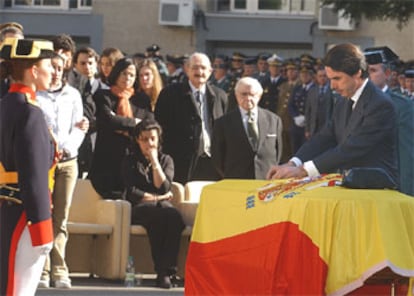 El presidente del Gobierno impone la cruz del mérito militar sobre el féretro con los restos del guardia civil.