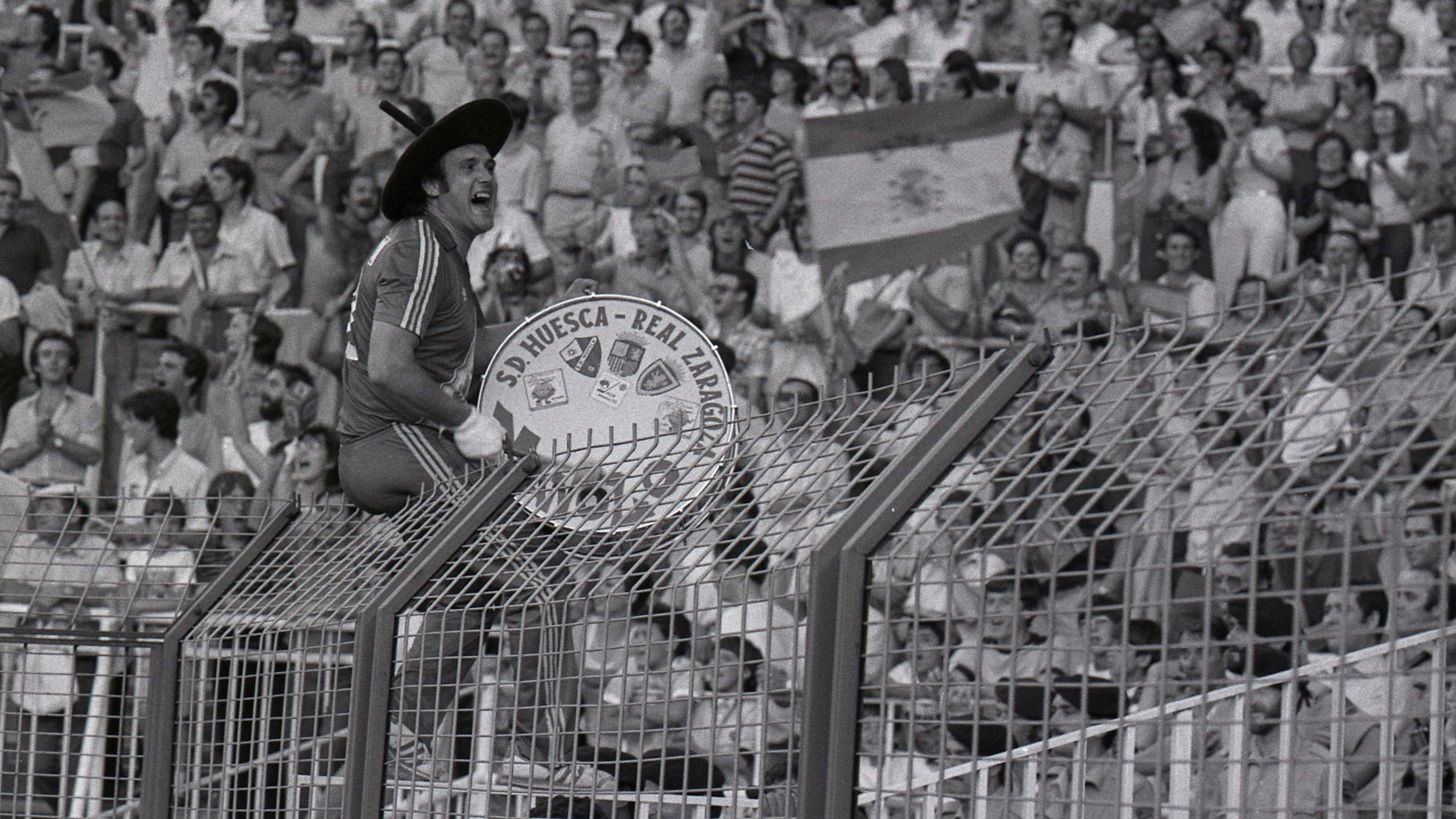 Manolo 'el del Bombo' arenga a la tribuna sentado sobre la valla del estadio Santiago Bernabéu. La España de Santillana, Camacho y Arconada sucumbía 1-2 ante la Alemania de Rummenigge y Stielike. La derrota eliminaba a la anfitriona en su primer encuentro de la segunda fase del Mundial 1982.
