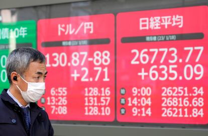 Un ciudadano japonés pasea cerca de unas pantallas con el tipo de cambio del yen en Tokyo.