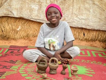 Rayan, una niña de 7 años que vive en el campo de tránsito de Adré, posa junto a su juego de té hecho por ella con barro que ha recogido por sí misma después de la lluvia.