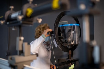 Una técnica realiza pruebas con una pantalla protectora en el laboratorio de óptica.