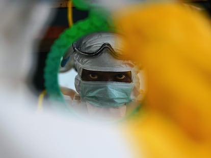 Un trabajador sanitario comprueba su equipo de protección en Kailahun (Sierra Leona) en agosto de 2014 durante el brote de ébola de África occidental.