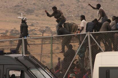Un grupo de inmigrantes subsaharianos se enfrentan a un policía tras saltar la valla de Melilla en el 2000