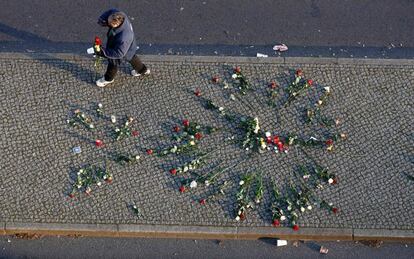 Un hombre sujeta unas flores cerca del mercadillo navideño donde se produjo en atentado en Berlín (Alemania), el 21 de diciembre de 2016.