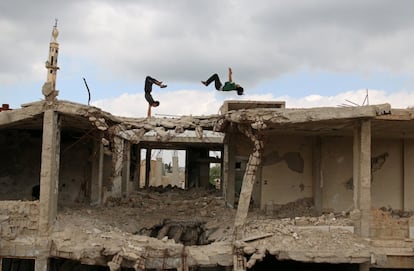 Saltando sobre techos destruidos por las bombas y a través de los marcos de las ventanas dañadas, un grupo de adolescentes corren y se abren camino a través de edificios abandonados por la guerra en la ciudad siria de Inkhil.