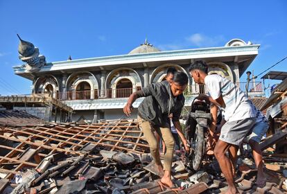 Varias personas transportan una motocicleta sobre el tejado de una mezquita dañada en Gunungsari, Lombok, el 6 de agosto de 2018. 