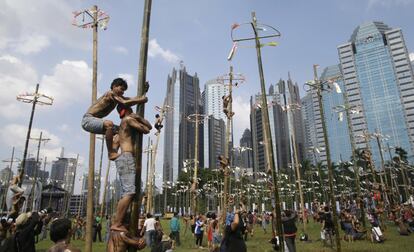 Hombres indonesios escalan por barras engrasadas para conseguir premios, durante el día de la Independencia en Jakarta (Indonesia).