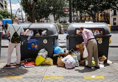 Dos hombres intentan dejar su basura en los contenedores llenos de la plaza de Tirso de Molina.