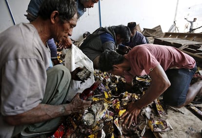 Hombres recolectan de una pila cualquier cosa comestible dentro de un almacén abandonado en Palu (Indonesia).