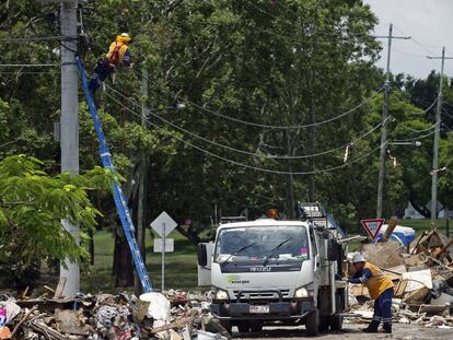 Dos operarios reparan líneas telefónicas dañadas por las inundaciones en Brisbane.