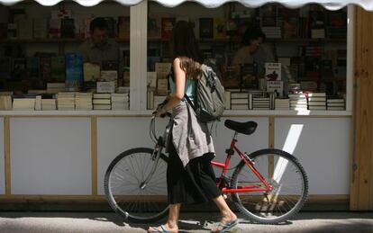 Una jove amb la se seua bicicleta passeja per la Fira del Llibre de Val&egrave;ncia.