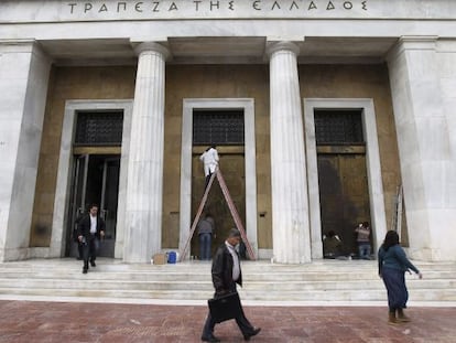 Varias personas pasan delante de la sede del Banco de Grecia. 