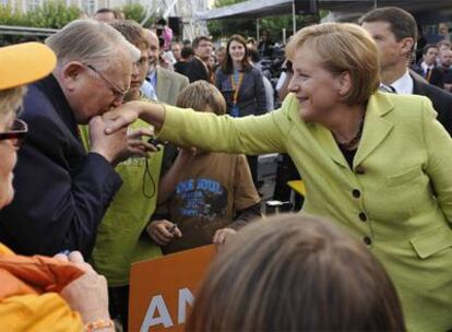 Un partidario de la CDU besa la mano a Merkel en un acto de campaña en el centro de Alemania.