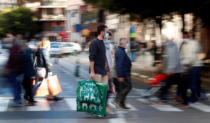 Varias personas cargan con sus bolsas tras realizar sus compras este domingo, a menos de dos semanas de celebrarse la navidad.