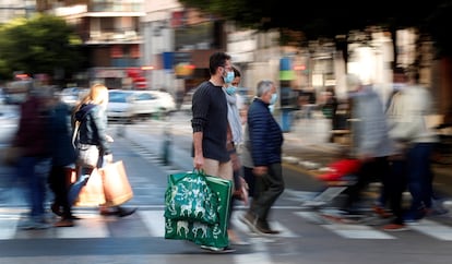 Varias personas cargan con sus bolsas tras realizar sus compras este domingo, a menos de dos semanas de celebrarse la navidad.