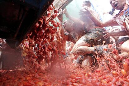 Un camión descarga tomates mientras una multitud de personas se avalanzan a recogerlos, en Buñol (Comunidad Valenciana).