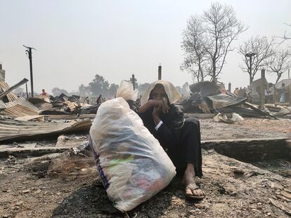 Una mujer rohinyá sentada en el suelo con sus pertenencias en una bolsa, tras el incendio que ha asolado el campamento Cox’s Bazar, en Bangladés.