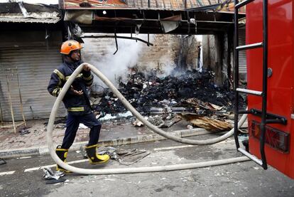 Un bombero participa en las labores de extinción de un incendio en una tienda de Minuwangda.