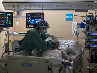 Una sanitaria atiende a un paciente con covid en la UCI del Hospital Vall d'Hebron de Barcelona