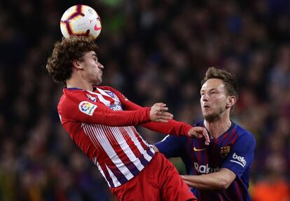 Antoine Griezmann cabecea el balón ante Ivan Rakitic durante un partido.