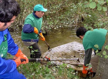 Tres voluntarios retiran un colchón de las aguas del río Rato, en el ayuntamiento de Lugo.