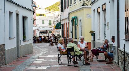 Vecinos de Es Mercadal conversan a la puerta de casa. Al fondo, la plaça de la Constitució.