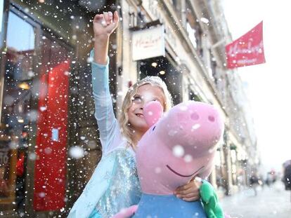 Una ni&ntilde;a con un peluche de Pepa Pig frente a la tienda de juguetes Hamleys, en Londres.