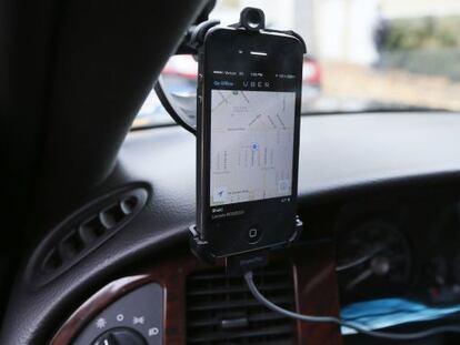 Un m&oacute;vil instalado en un coche muestra la aplicaci&oacute;n de Uber 